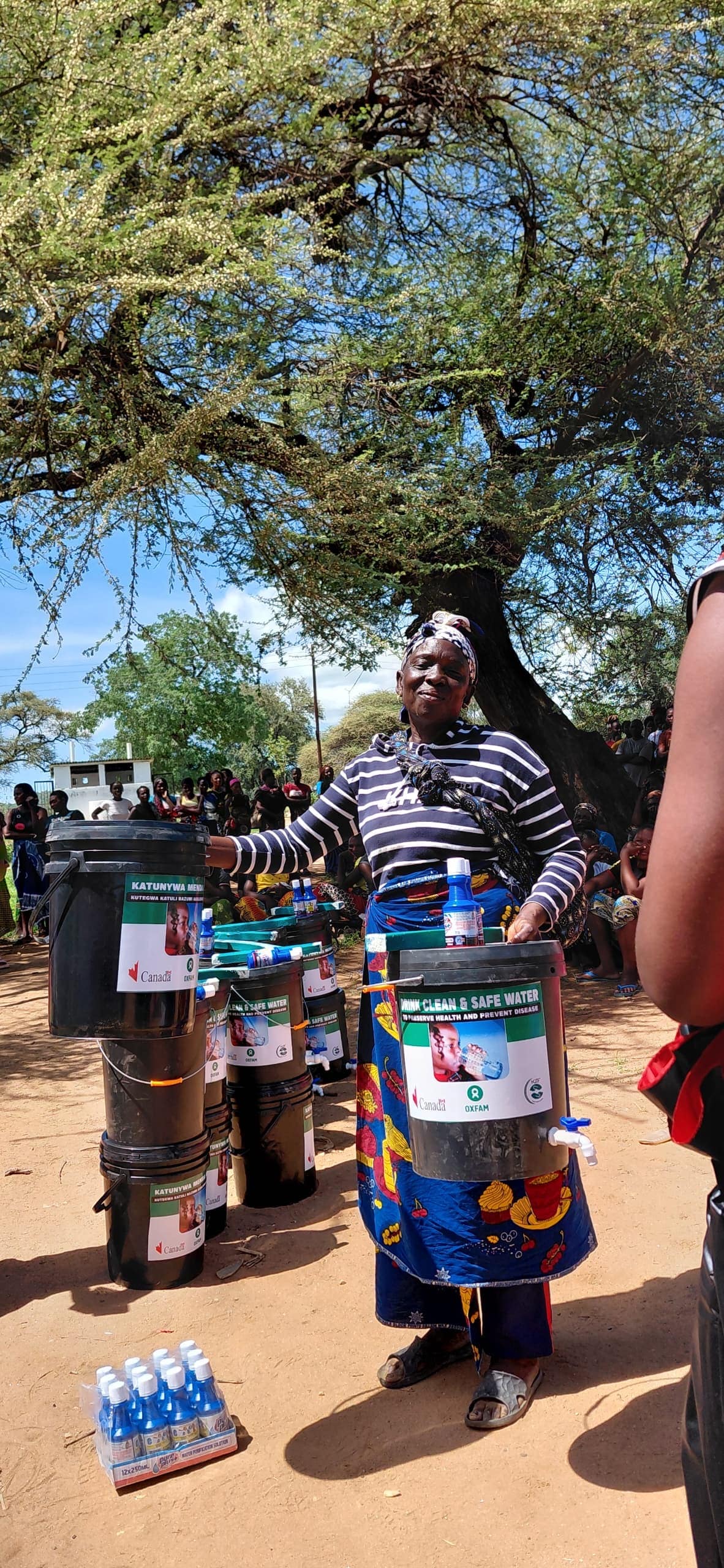 Woman receiving water storage bucket during community distribution in Zambia