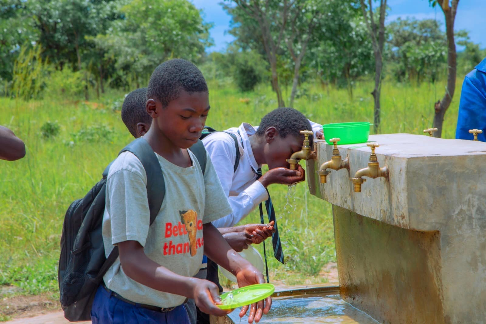 Children using a clean water tap at a rural water point in Zambia