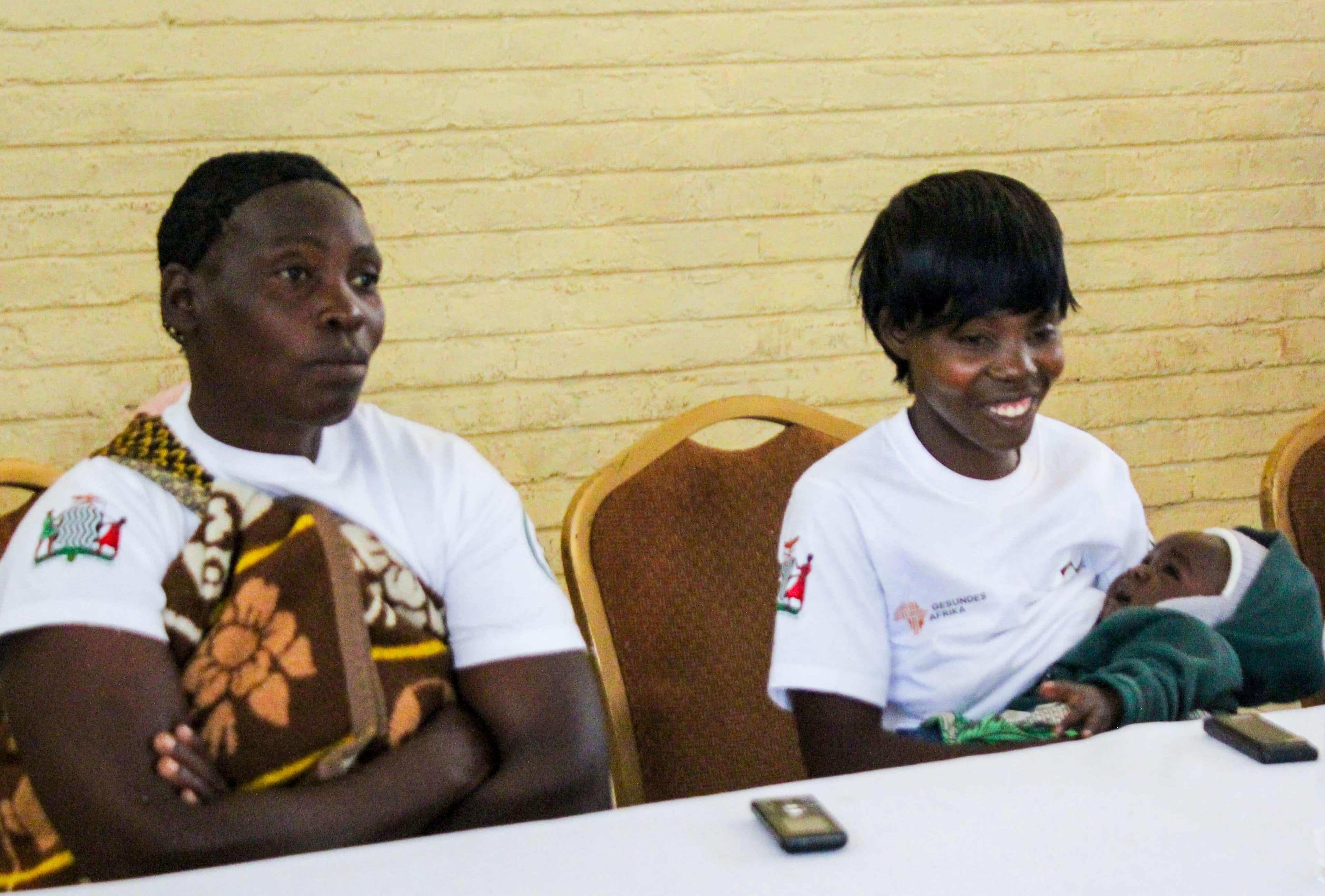 Two participants smile as they listen to a presentation.